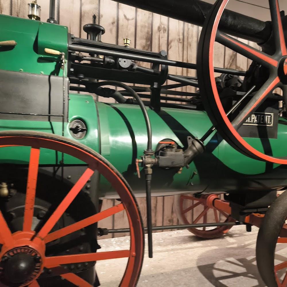 A green vintage steam engine with a large red wheel.